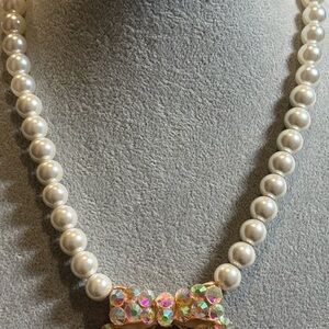 Elegant faux Pearl Necklace with crystal embellished gold bow pendant!